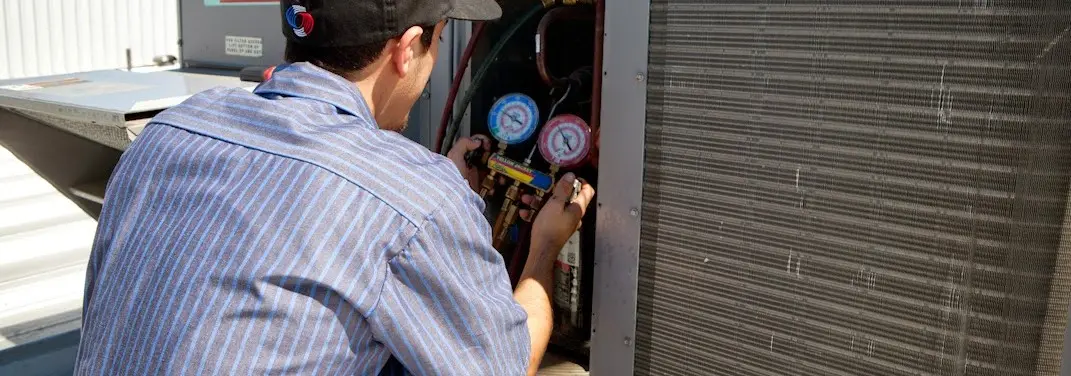 HVAC technician servicing a condenser unit in Waianae